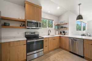 Kitchen with open shelves, stainless steel appliances, a peninsula, light stone countertops, and decorative light fixtures