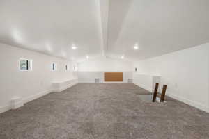 Additional living space with dark colored carpet and beamed ceiling