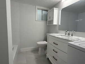 Full bath with vanity, a textured ceiling, and washer / clothes dryer