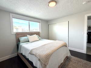Bedroom with a closet, a textured ceiling, and dark wood-style floors