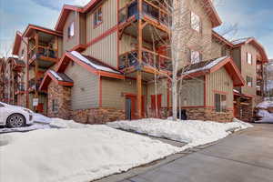 View of front of property featuring stone siding, a balcony, and board and batten siding