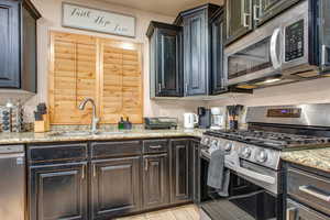 Kitchen featuring stainless steel appliances, light stone counters, and light wood-style floors