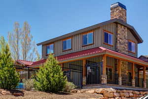 Back of property featuring board and batten siding, a metal roof, a porch, and a chimney