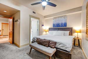 Carpeted bedroom with ceiling fan and baseboards