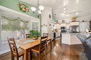 Dining room featuring dark wood-style flooring, lofted ceiling, and hanging lights