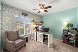Home office with carpet, ceiling fan, and a textured ceiling