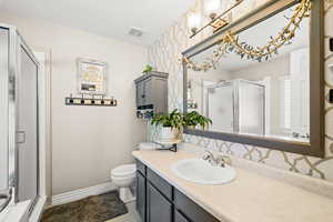 Bathroom featuring vanity, a shower stall, and wallpapered walls
