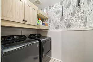 Laundry room featuring washing machine and dryer, cabinet space, and a textured ceiling