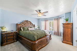 Bedroom featuring light colored carpet, ceiling fan, and a textured ceiling