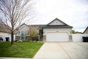 Traditional-style house featuring an attached garage, driveway, stucco siding, a shingled roof, and stone siding