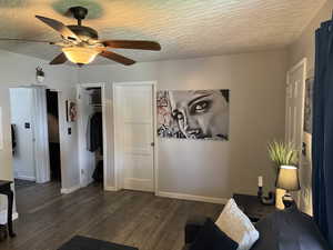 Bedroom with ceiling fan, dark wood-type flooring, a walk in closet, and a textured ceiling
