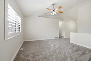 Empty room with light colored carpet, lofted ceiling, and ceiling fan