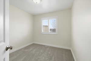 Empty room with light colored carpet and baseboards