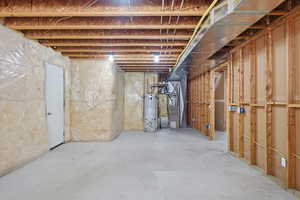 Unfinished basement featuring strapped water heater and heating unit