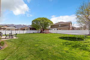 Fenced backyard with a trampoline, a patio, and a mountain view