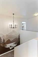 Corridor featuring hanging lights and carpet flooring