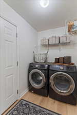 Laundry room featuring independent washer and dryer, light wood-style flooring, and a textured ceiling
