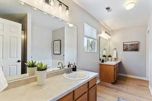 Bathroom featuring two vanities and light wood finished floors