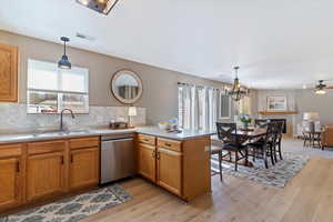 Kitchen featuring a peninsula, light countertops, stainless steel dishwasher, and open floor plan