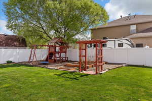 Fenced backyard with a garden and a playground