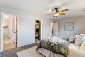 Bedroom featuring a walk in closet, light colored carpet, and ceiling fan