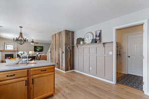 Kitchen with light countertops, a chandelier, a warm lit fireplace, light wood-style flooring, and open floor plan