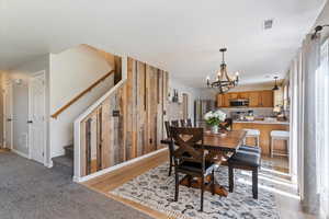 Dining space with suspended lighting, light wood-style flooring, and wooden walls