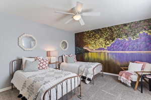 Bedroom with an accent wall, light carpet, and a ceiling fan
