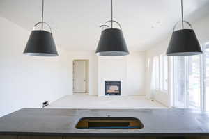 Kitchen with a fireplace, hanging light fixtures, light stone counters, and open floor plan