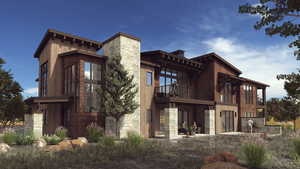 Rear view of property featuring stone siding and a balcony