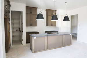 Kitchen featuring a kitchen island with sink, pendant lighting, wood finish cabinets, and a kitchen bar
