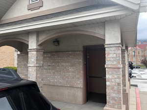 Entrance to property with stucco siding, elevator, and brick siding