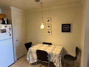 Dining room with light tile patterned floors, crown molding, and a textured ceiling