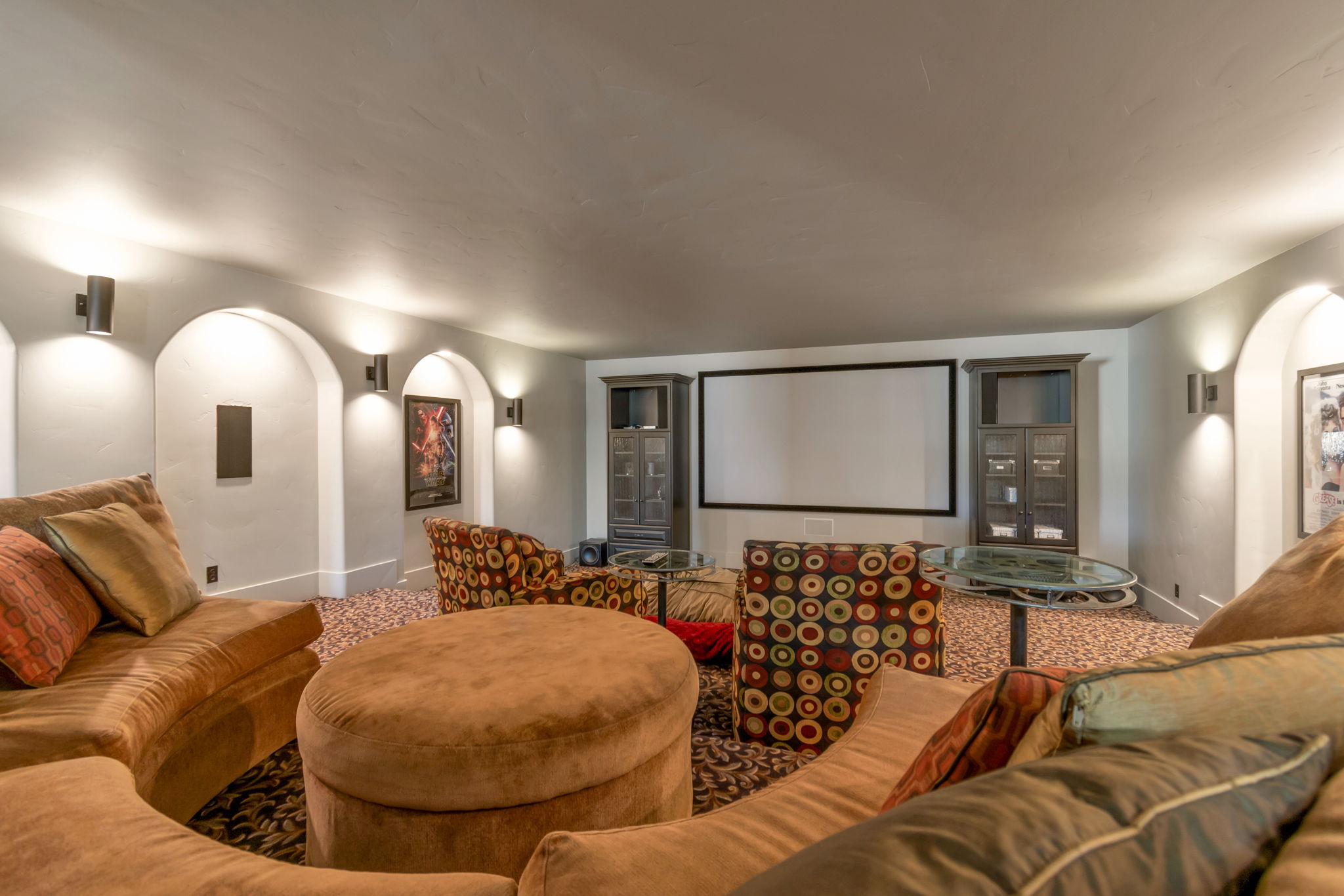 Carpeted home theater room featuring arched walkways and baseboards