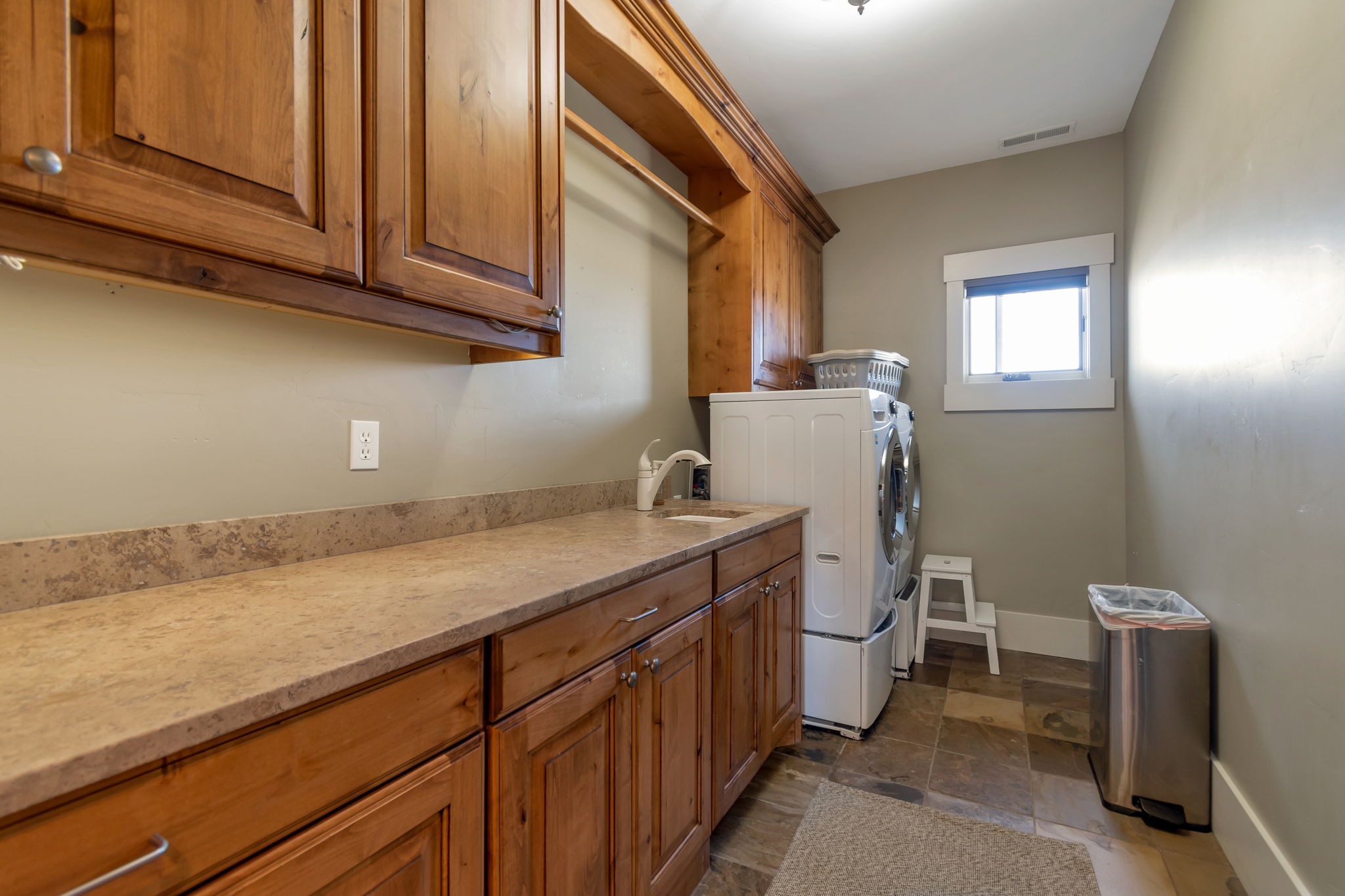 Laundry area featuring cabinet space, dark stone finish flooring, and washing machine and dryer