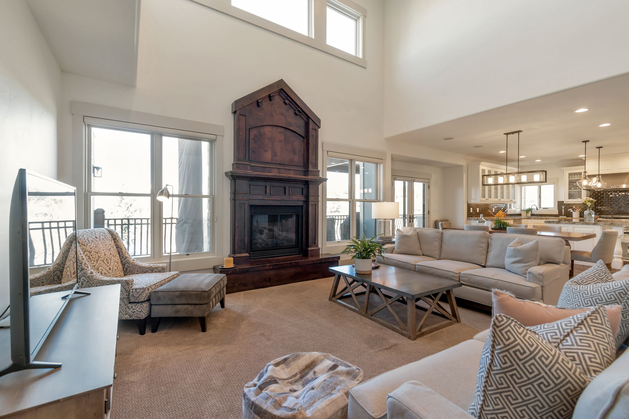 Carpeted living area with a glass covered fireplace, a high ceiling, and recessed lighting