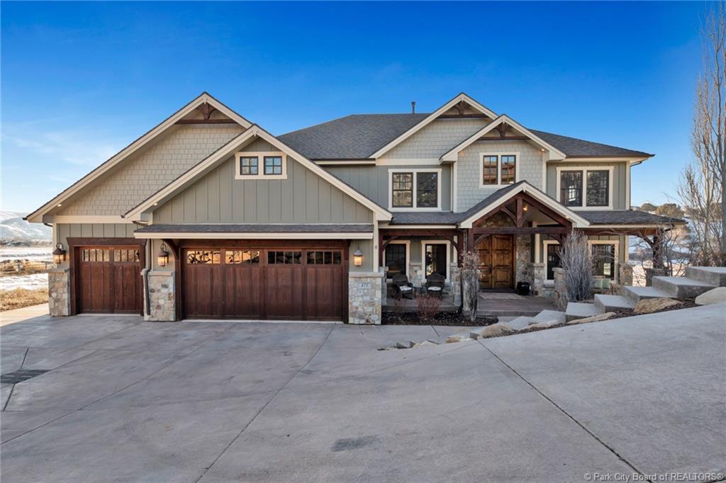 Craftsman-style home featuring stone siding, a porch, driveway, board and batten siding, and a garage