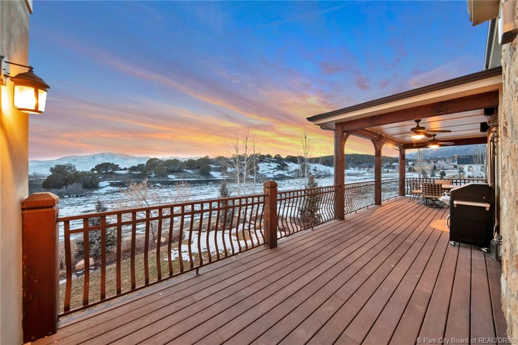 Snow covered deck with a mountain view, a ceiling fan, and area for grilling