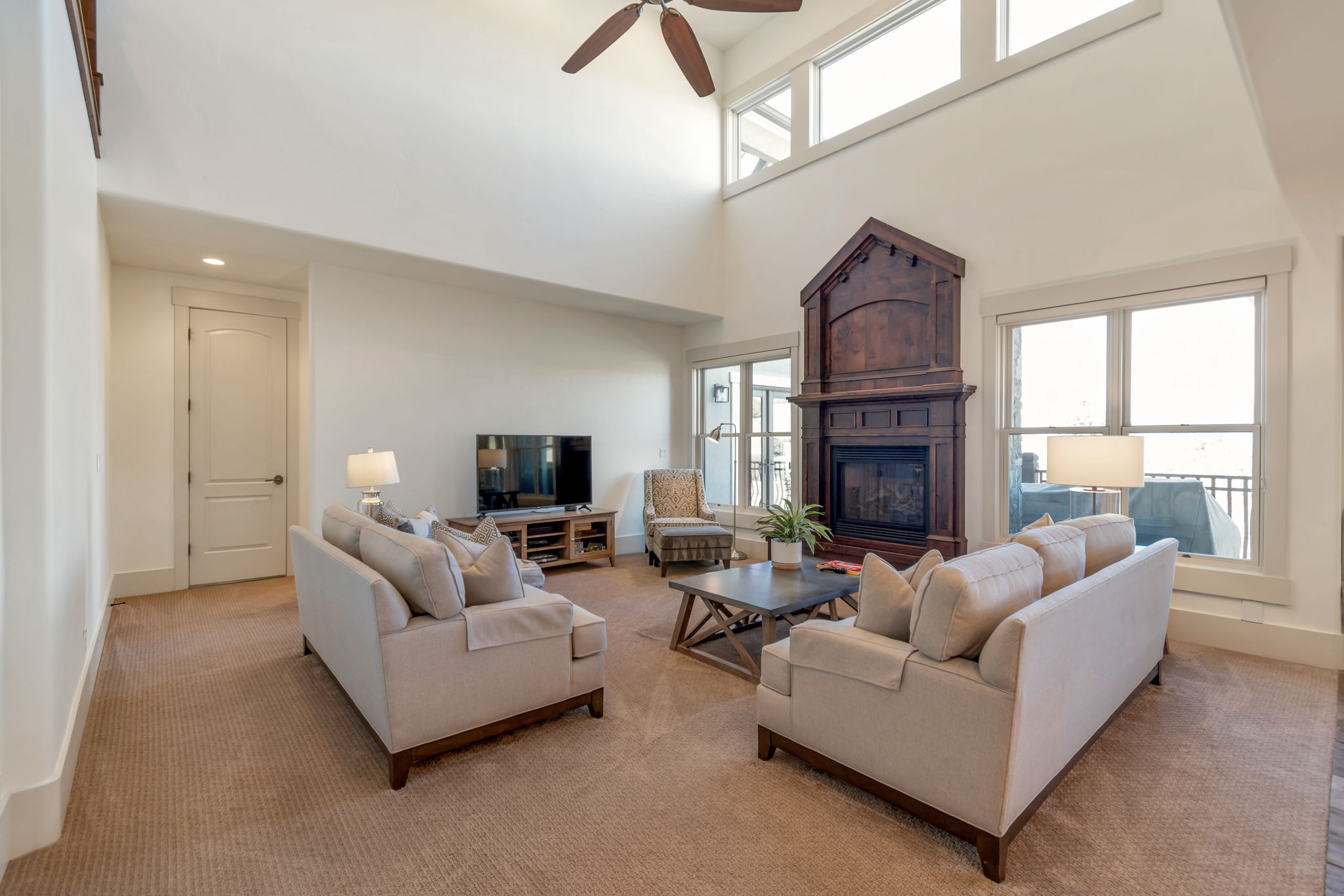 Living room featuring carpet, ceiling fan, a glass covered fireplace, and a high ceiling
