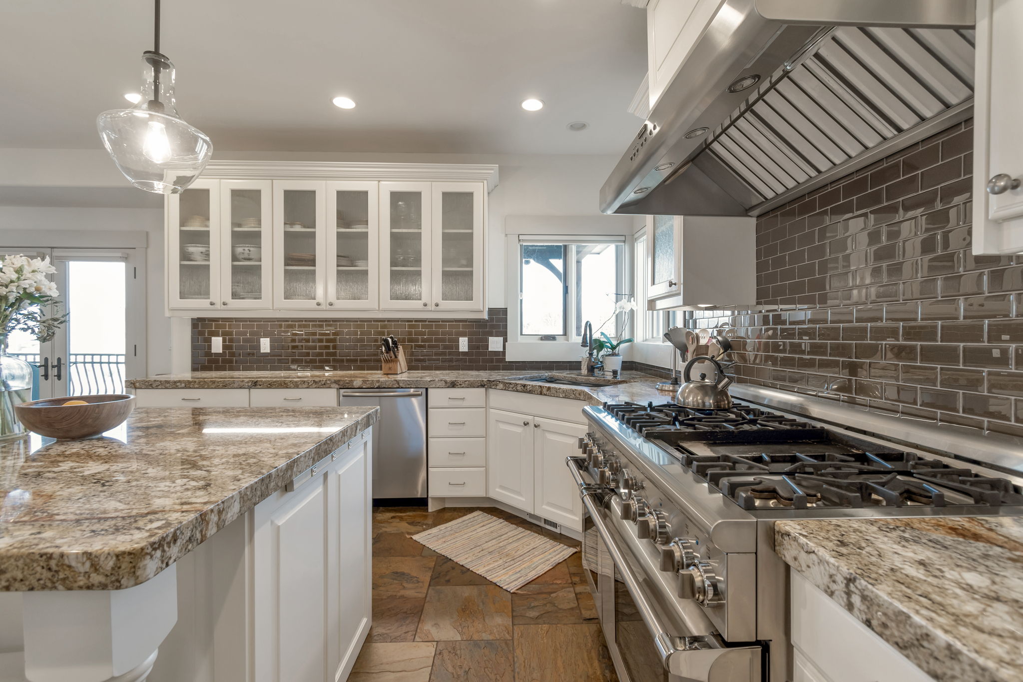Kitchen featuring stainless steel appliances, extractor fan, white cabinetry, glass insert cabinets, and tasteful backsplash