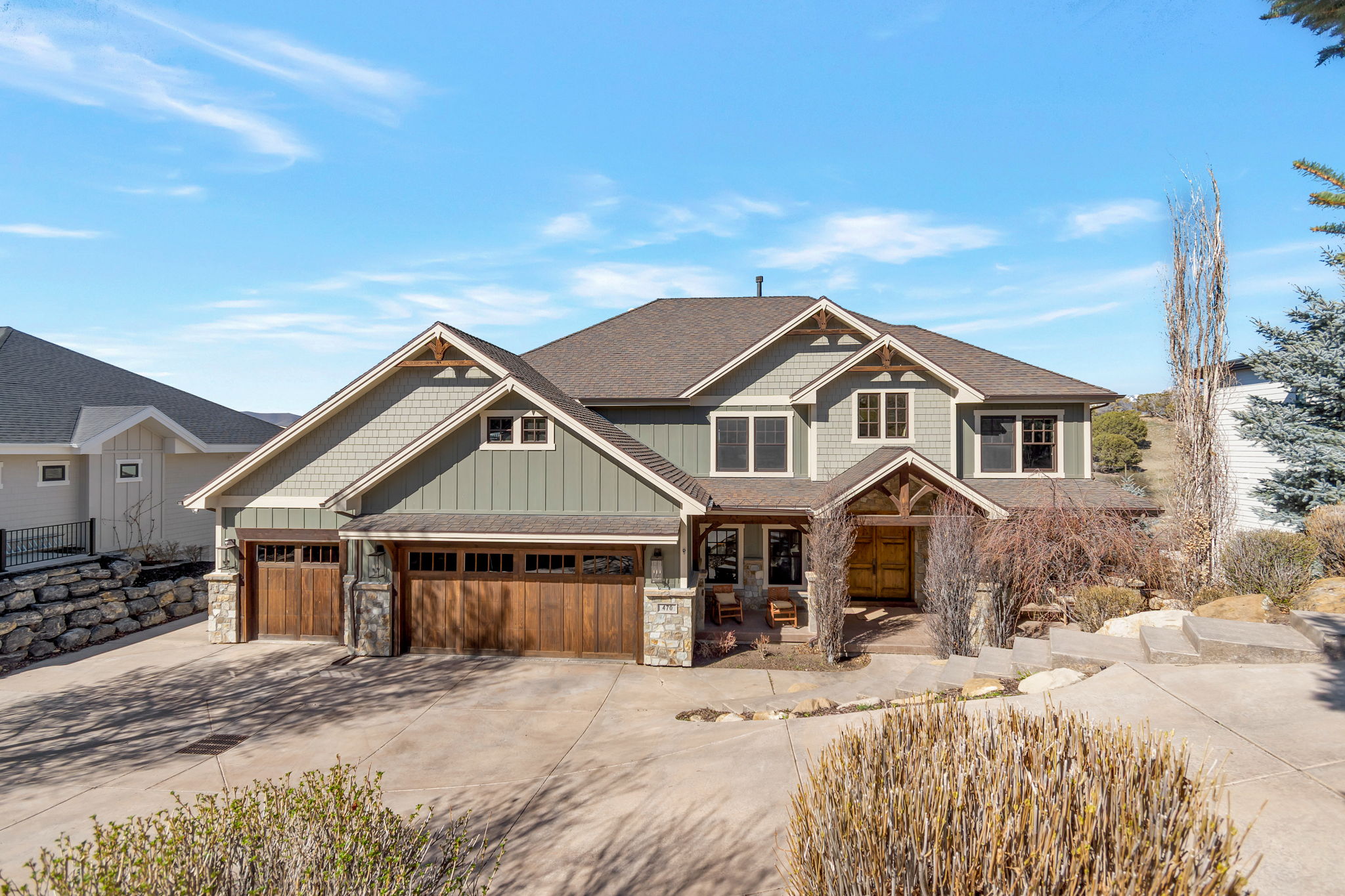Craftsman-style home featuring driveway, board and batten siding, covered porch, and stone siding