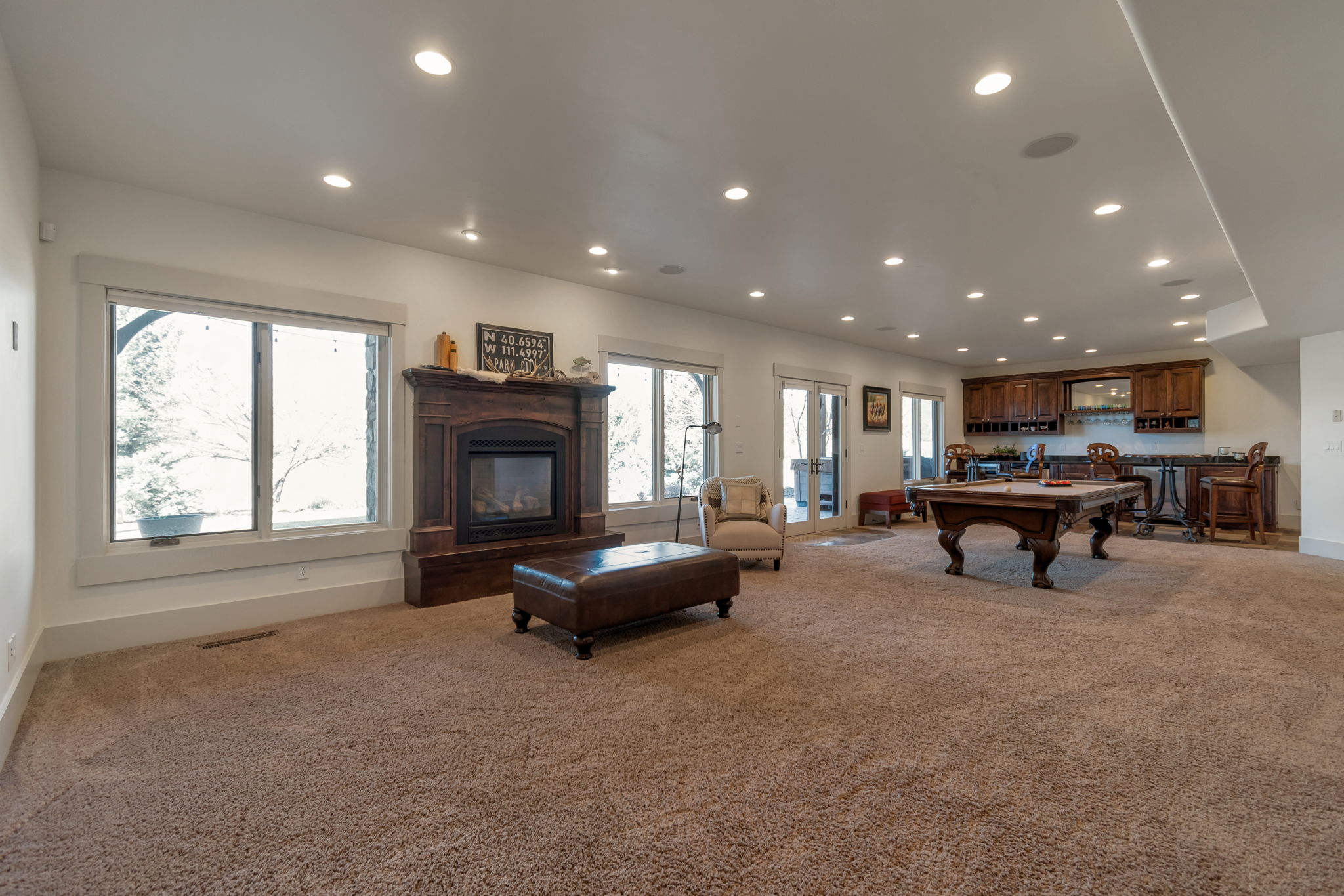 Living area with recessed lighting, light carpet, a glass covered fireplace, billiards table, and bar
