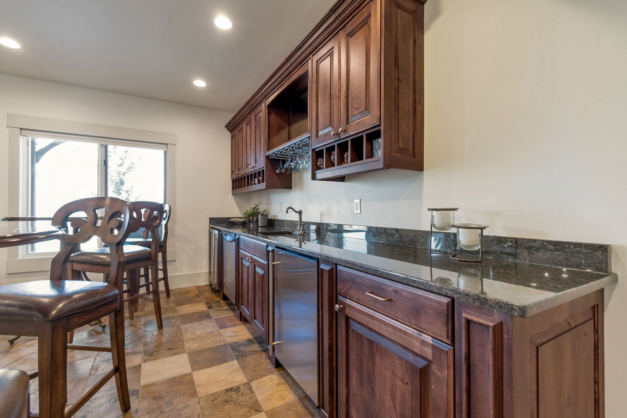 Kitchen with open shelves, dark stone countertops, stainless steel dishwasher, recessed lighting, and dark wood finish cabinets