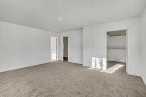 Unfurnished bedroom with a spacious closet and light colored carpet