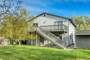Rear view of property featuring a lawn and a wooden deck
