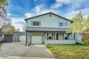 Traditional-style house with roof with shingles, concrete driveway, an attached garage, a front lawn, and a porch