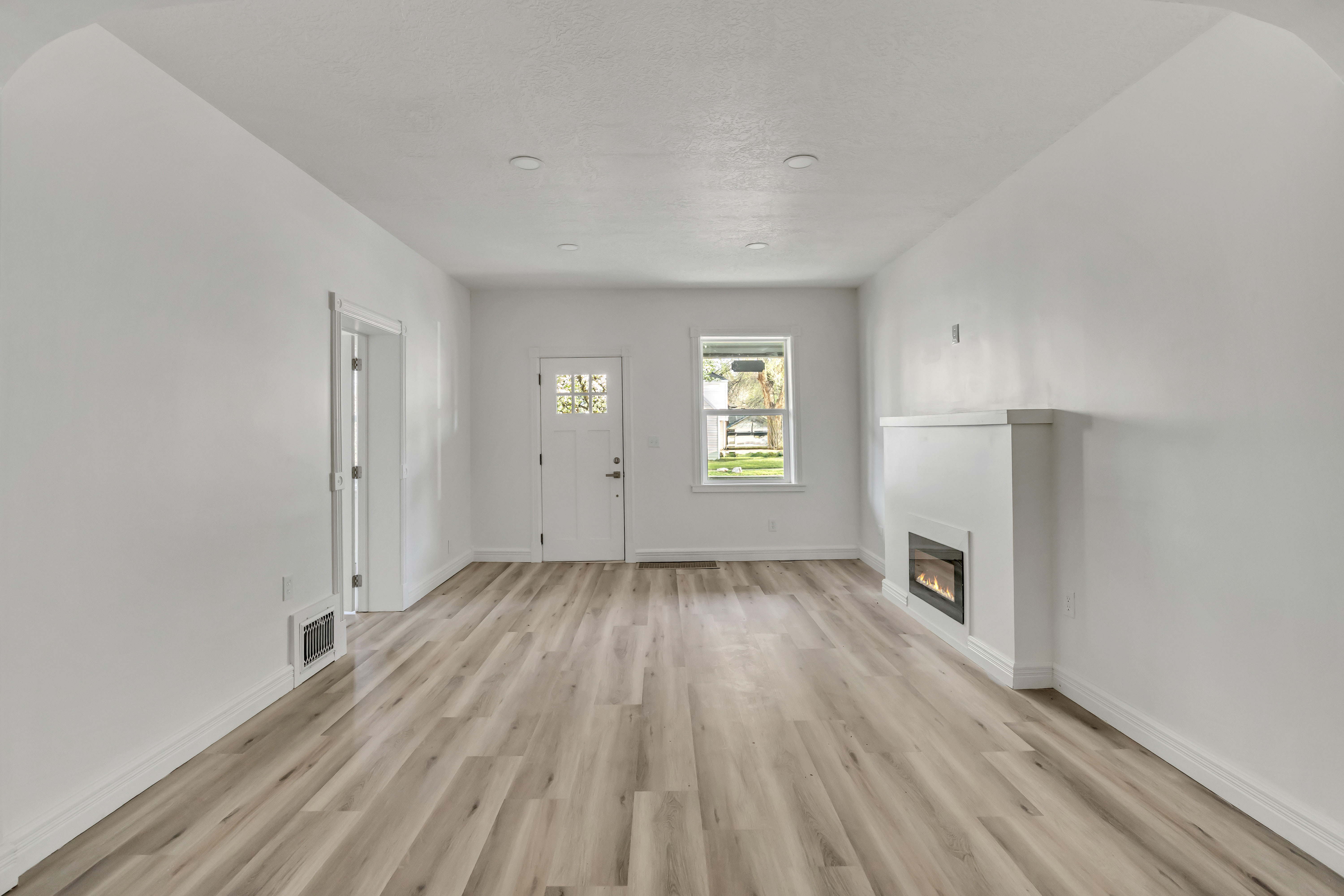 Unfurnished living room featuring a glass covered fireplace and light wood-style flooring