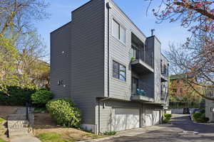 View of side of home featuring a balcony, a garage, and asphalt driveway