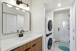 Bathroom featuring vanity, a closet, a stall shower, stacked washer and dryer, and recessed lighting