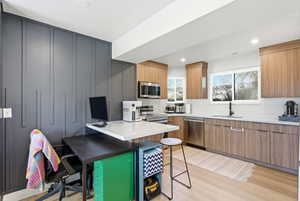 Kitchen featuring a kitchen bar, a peninsula, stainless steel appliances, light wood finished floors, and modern cabinets